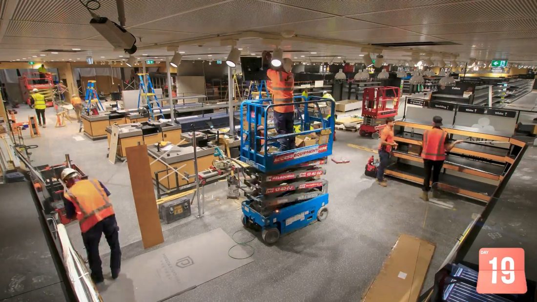 Interior construction of an ALDI supermarket showing refurbishment works with exposed ceiling, lighting installation, shelving frames, and unfinished flooring.
